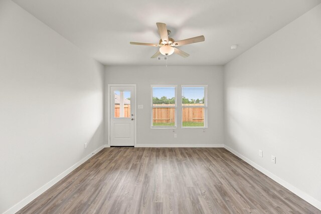 unfurnished room with baseboards, visible vents, ceiling fan, and wood finished floors