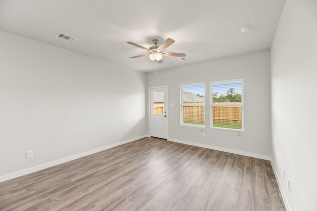 unfurnished room with baseboards, visible vents, wood finished floors, and ceiling fan