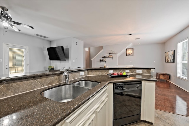 kitchen featuring dishwasher, hanging light fixtures, dark stone counters, light tile patterned flooring, and sink