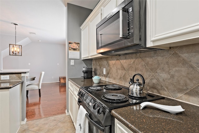 1211 Ennis St, Houston, TX 77003 - kitchen featuring stainless steel microwave, black range with electric stovetop, white cabinetry, a chandelier, and backsplash