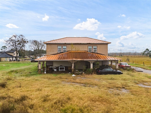 exterior space with a rural view, a carport, and a lawn