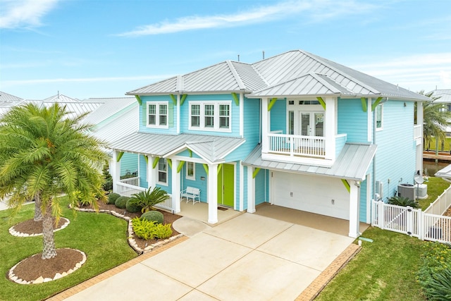 raised beach house with a porch, a balcony, a front yard, and a garage