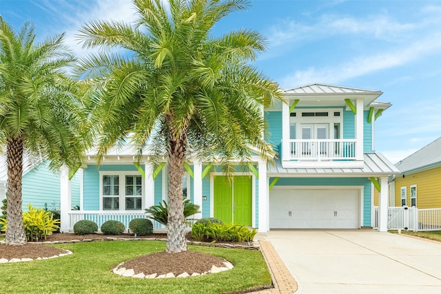 coastal inspired home featuring a balcony, a garage, and a front lawn