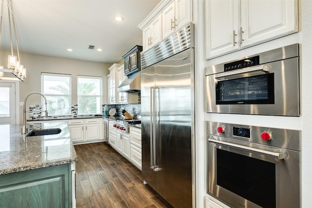 kitchen with sink, white cabinets, light stone counters, tasteful backsplash, and appliances with stainless steel finishes