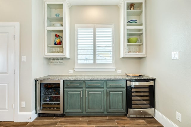 bar with beverage cooler, white cabinetry, and light stone counters