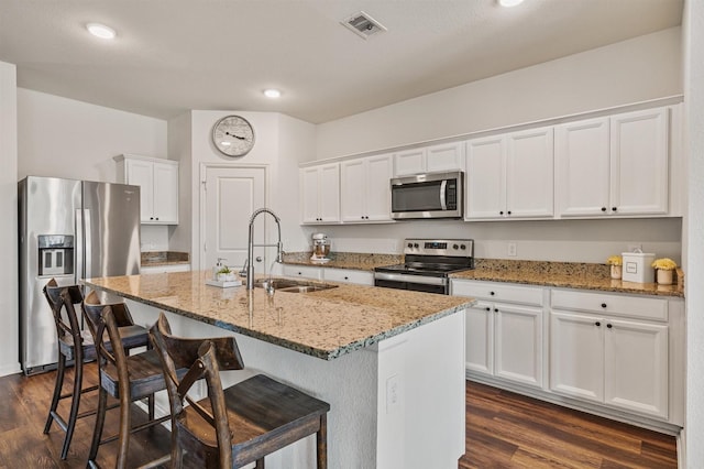 kitchen featuring visible vents, white cabinets, dark wood-type flooring, stainless steel appliances, and a sink