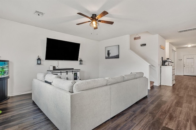 living room featuring stairway, dark wood-style flooring, visible vents, and a ceiling fan