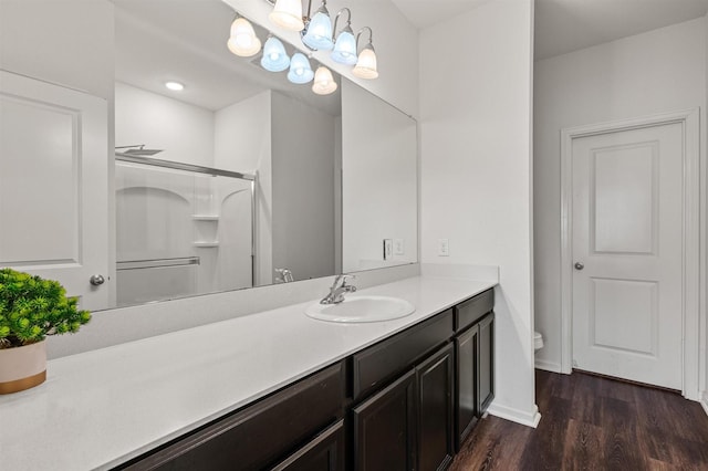 full bath featuring baseboards, a shower, toilet, wood finished floors, and vanity