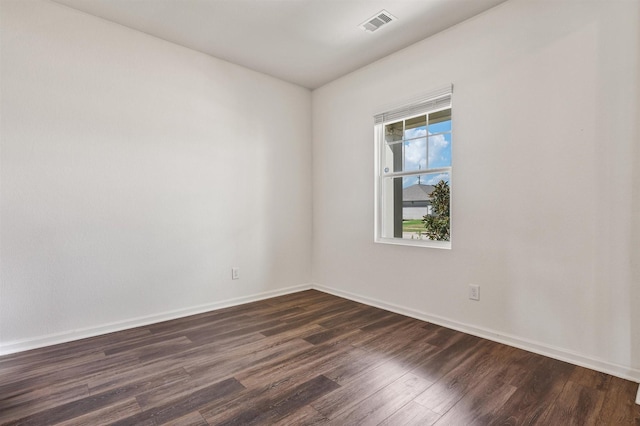 empty room featuring dark wood finished floors, visible vents, and baseboards