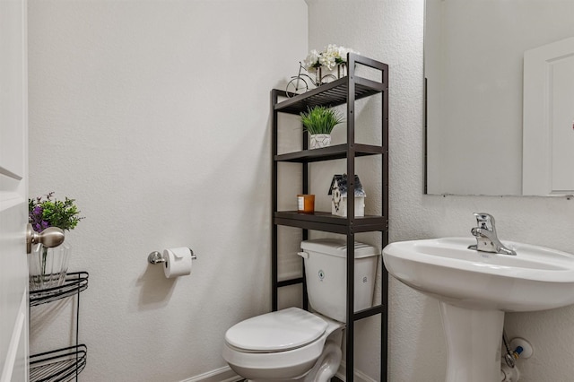 bathroom with a textured wall, a sink, and toilet