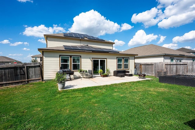 rear view of house featuring solar panels, a lawn, a patio area, and a fenced backyard