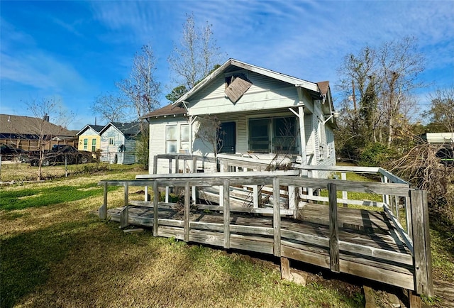 back of property featuring a deck and a lawn