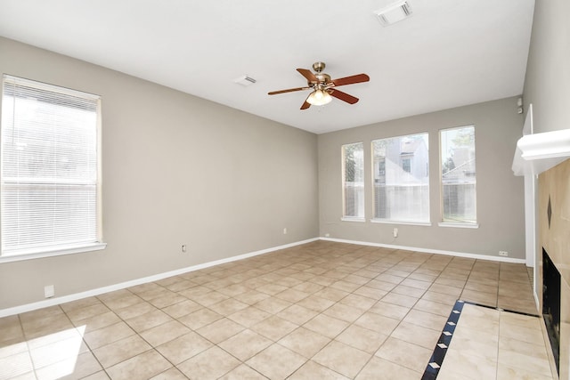 unfurnished living room featuring ceiling fan, a tiled fireplace, and light tile patterned floors