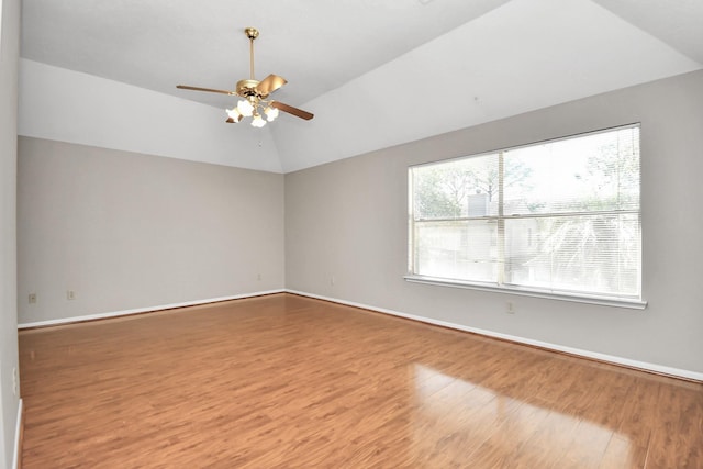 empty room with ceiling fan, hardwood / wood-style floors, and vaulted ceiling