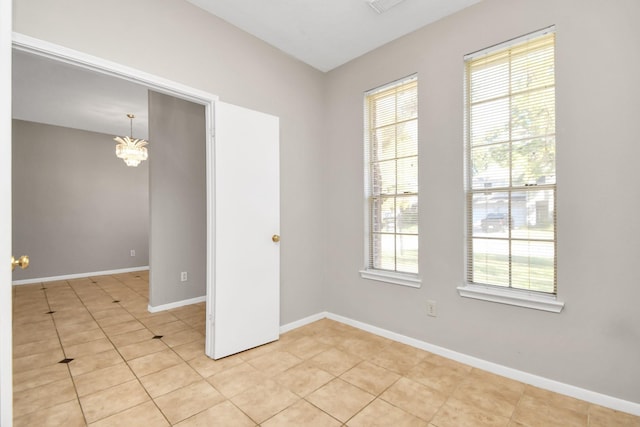 tiled spare room featuring an inviting chandelier and a wealth of natural light