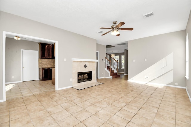 unfurnished living room with ceiling fan, a tile fireplace, and light tile patterned flooring