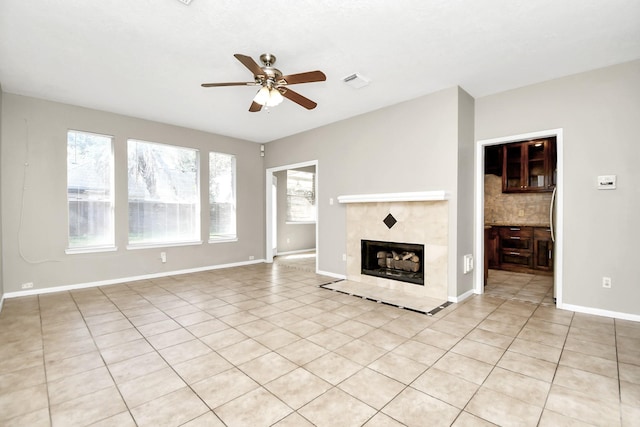 unfurnished living room featuring a fireplace, ceiling fan, and light tile patterned floors