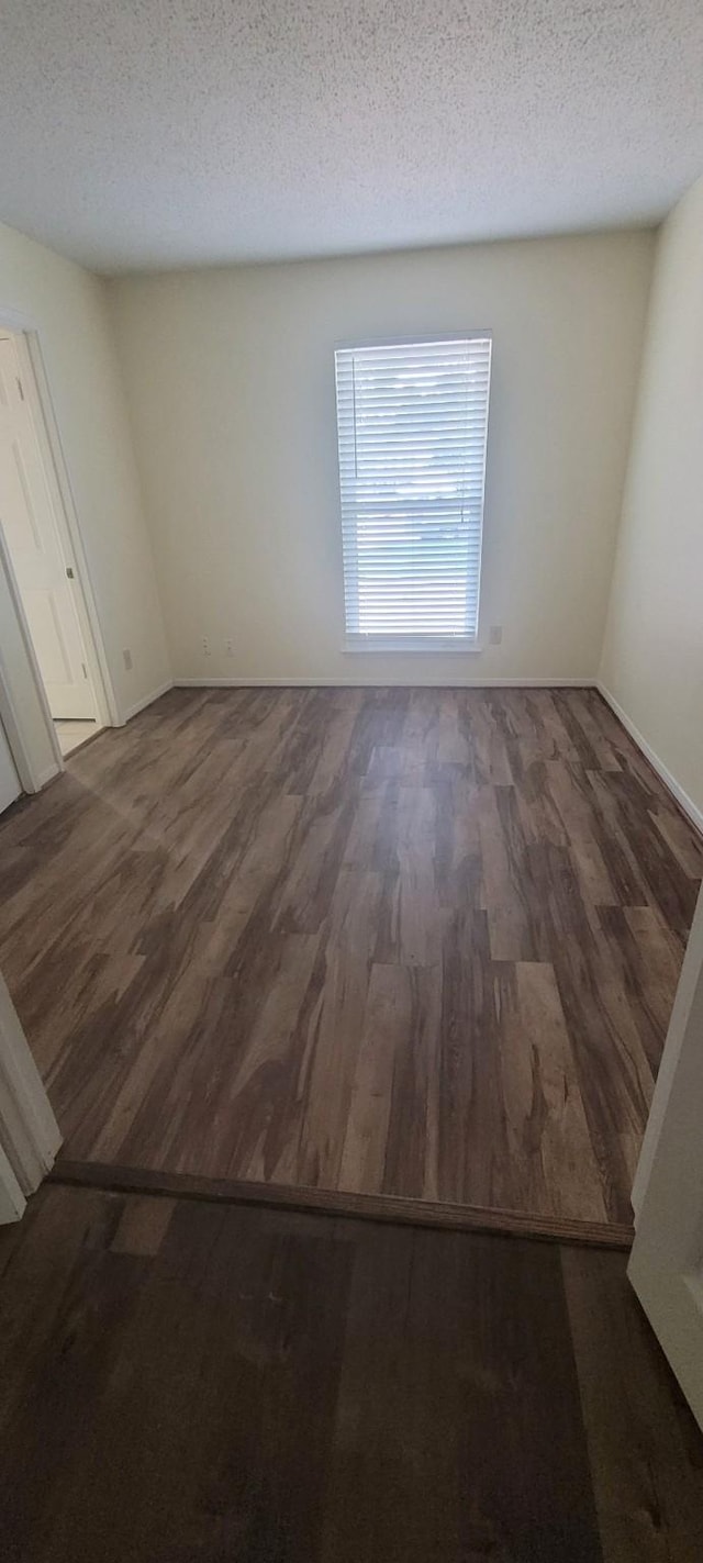 spare room with a textured ceiling and dark hardwood / wood-style flooring