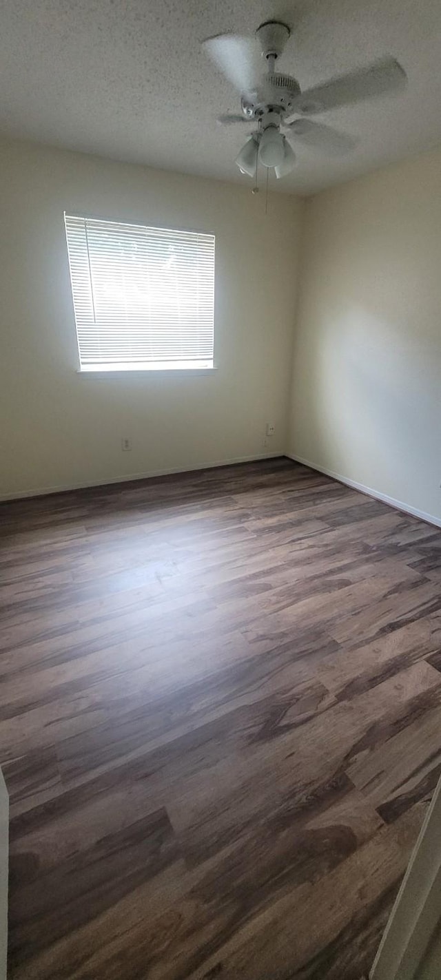 empty room featuring ceiling fan, a textured ceiling, and dark hardwood / wood-style flooring