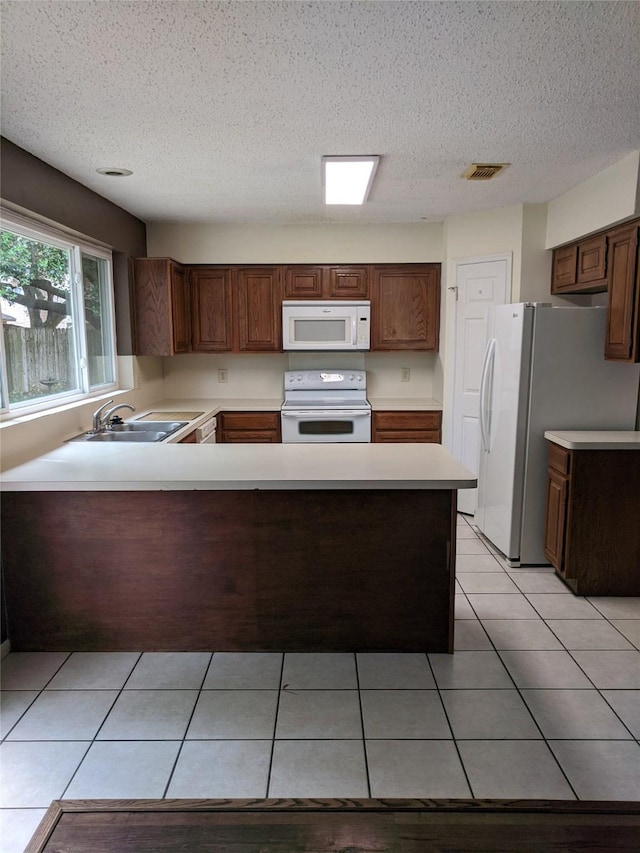 kitchen with white appliances, a textured ceiling, sink, kitchen peninsula, and light tile patterned flooring