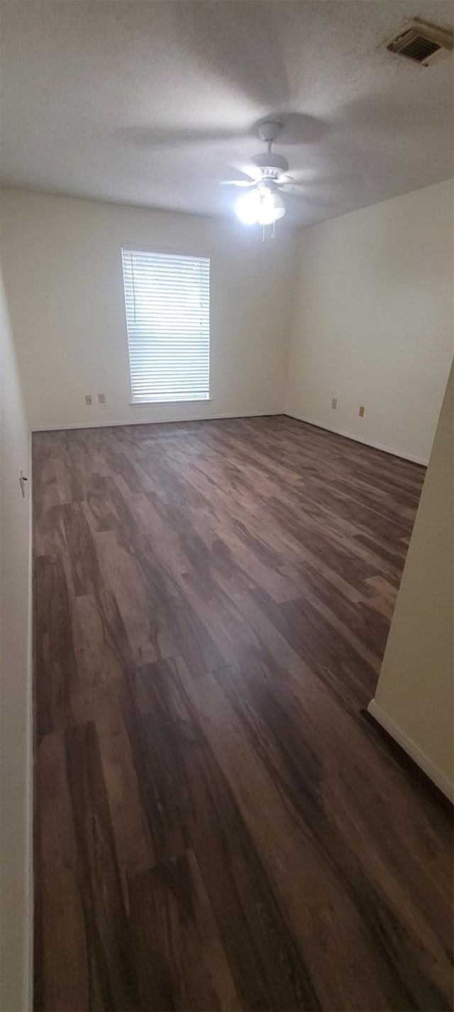 unfurnished room with a textured ceiling, dark hardwood / wood-style floors, and ceiling fan