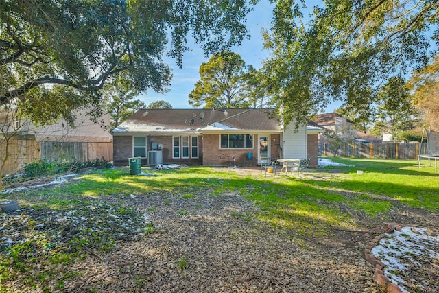 back of house with a trampoline, central AC unit, and a lawn