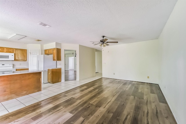 16002 Maple Acres Ct, Houston, TX 77095 - kitchen with white appliances, brown cabinets, open floor plan, light wood finished floors, and light countertops