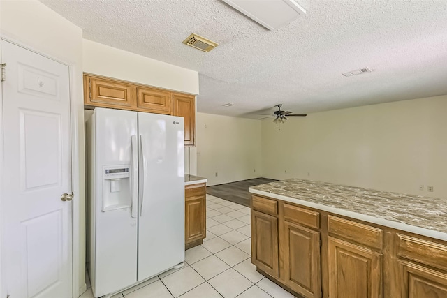 16002 Maple Acres Ct, Houston, TX 77095 - kitchen with white refrigerator with ice dispenser, a ceiling fan, brown cabinetry, light tile patterned floors, and light countertops