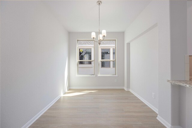 unfurnished dining area with light hardwood / wood-style flooring and an inviting chandelier