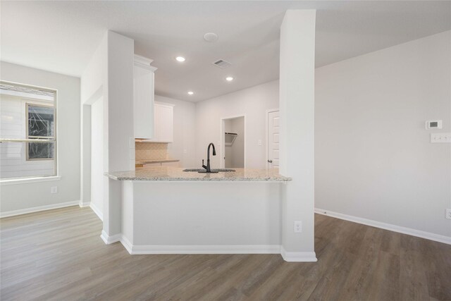 kitchen featuring sink, white cabinets, hardwood / wood-style floors, and light stone countertops