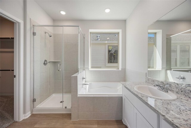 bathroom with plus walk in shower, vanity, and wood-type flooring