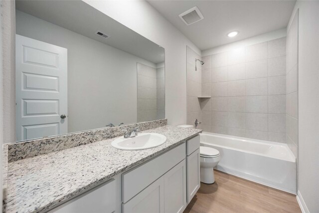 full bathroom featuring tiled shower / bath, toilet, vanity, and wood-type flooring