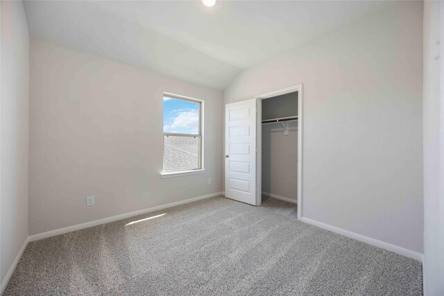 unfurnished bedroom with a closet, lofted ceiling, and carpet