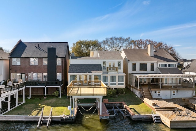 back of house with a lawn and a deck with water view