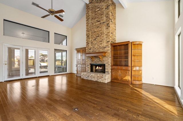 unfurnished living room featuring dark hardwood / wood-style floors, a towering ceiling, a fireplace, ceiling fan, and beamed ceiling