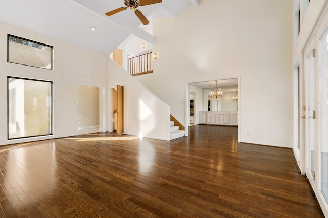 unfurnished living room with ceiling fan with notable chandelier, high vaulted ceiling, beamed ceiling, and dark wood-type flooring