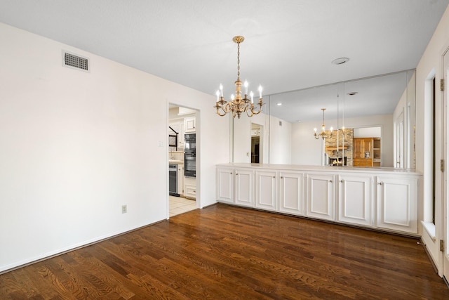 unfurnished dining area with hardwood / wood-style floors and a chandelier