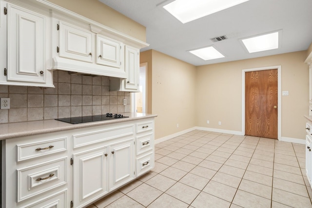 kitchen featuring light tile patterned flooring, black electric stovetop, backsplash, and white cabinetry