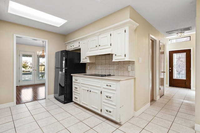 kitchen with light tile patterned floors, white cabinetry, backsplash, and black appliances