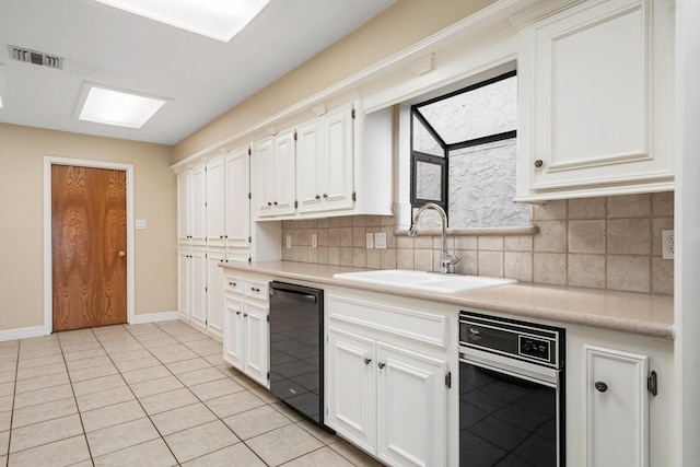 kitchen with white cabinets, light tile patterned floors, sink, black dishwasher, and tasteful backsplash