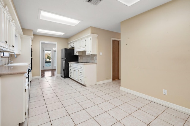 kitchen with sink, light tile patterned floors, white cabinetry, and backsplash