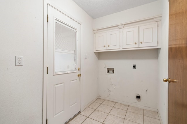 laundry room featuring a textured ceiling, hookup for an electric dryer, hookup for a washing machine, cabinets, and light tile patterned flooring