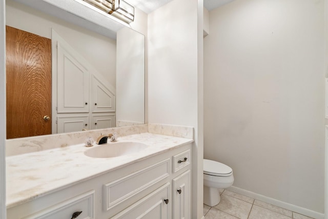 bathroom with toilet, vanity, and tile patterned flooring