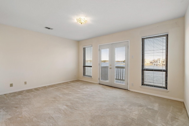 carpeted spare room featuring french doors and plenty of natural light