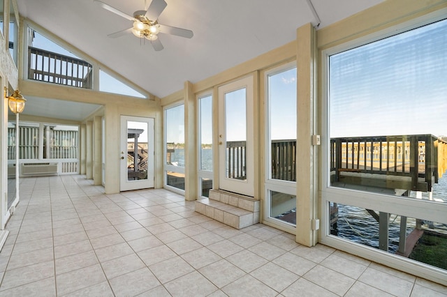 unfurnished sunroom featuring lofted ceiling, ceiling fan, a wealth of natural light, and a water view