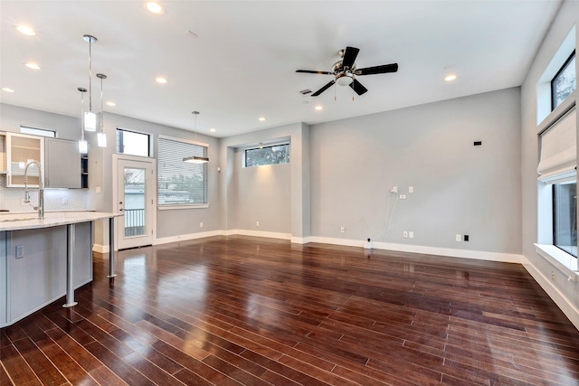 unfurnished living room featuring ceiling fan, dark wood-type flooring, and sink