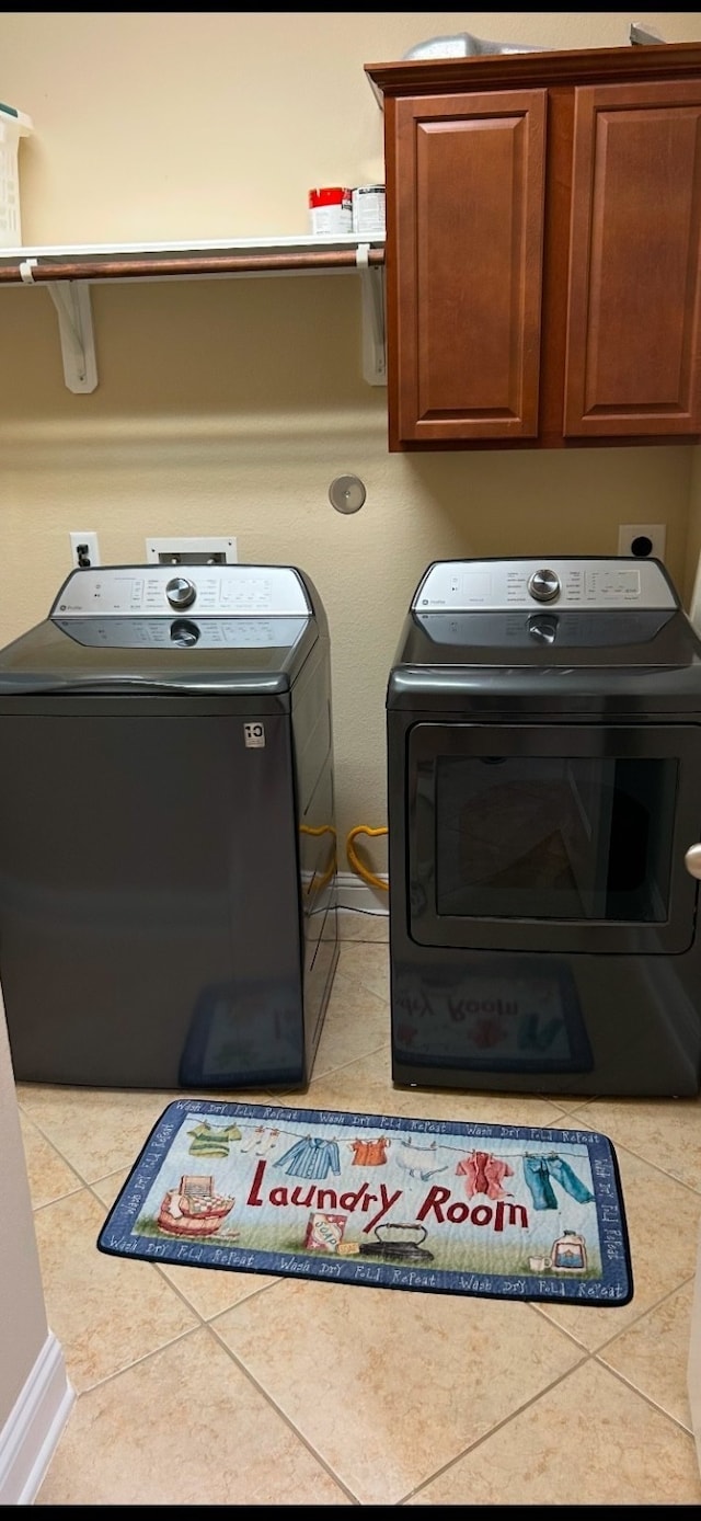 laundry area featuring independent washer and dryer, cabinets, and tile patterned floors