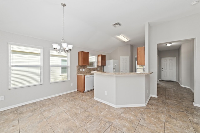 kitchen with white appliances, kitchen peninsula, an inviting chandelier, lofted ceiling, and tasteful backsplash