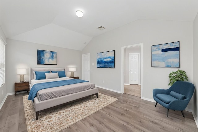 bedroom featuring vaulted ceiling, multiple windows, and hardwood / wood-style flooring