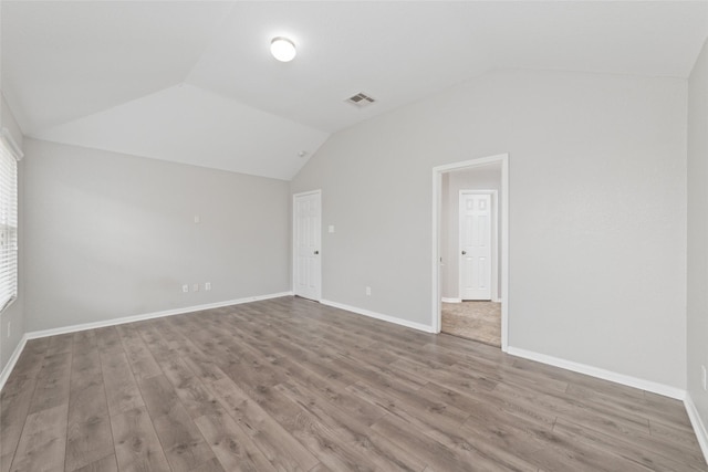 spare room with hardwood / wood-style floors and lofted ceiling